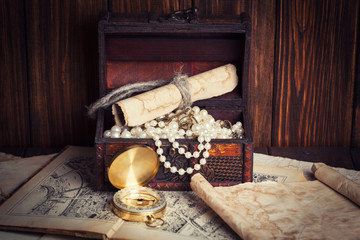 treasure chest, compass and old map on wooden table