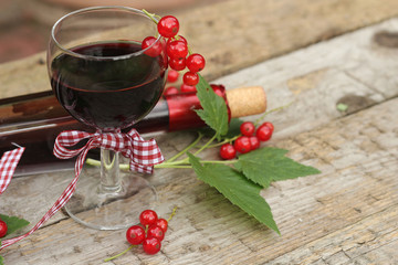Red currant wine in glass on wooden background