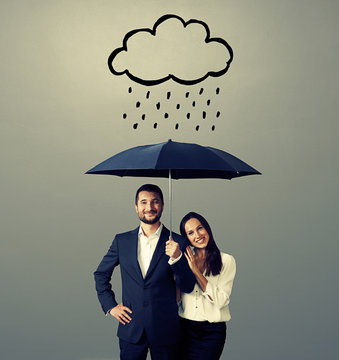 smiley young couple with black umbrella
