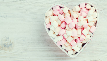 marshmallows in heart shape bowl on a wooden table