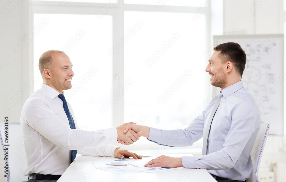 Wall mural two smiling businessmen shaking hands in office