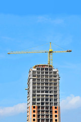 Crane and building construction site against blue sky