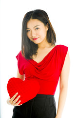 Portrait of a young woman holding heart shape cushion