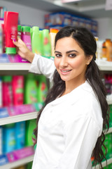 young woman holding bottle of shampoo in supermarket