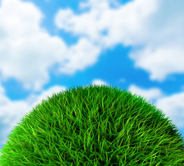 Green grass ball on blue sky with clouds