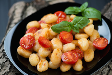 Close-up of roasted gnocchi and cherry tomatoes with green basil