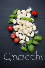 Above view of raw gnocchi with tomatoes and green basil leaves
