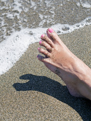 woman feet relaxing on the shore waiting for the sea foam