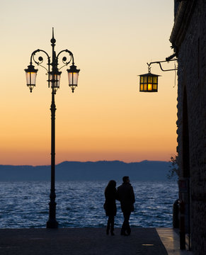 Silhouette of a couple on the shore of lake Garda, Italy.