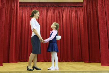 Happy mother and daughter hold hands and look at each other