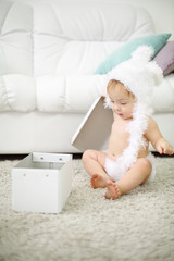 Pretty baby in white soft hat holds cover for white box