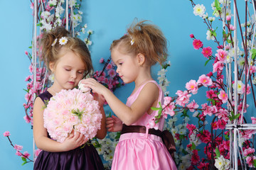 Two cute little girls in dresses make up bouquet of roses
