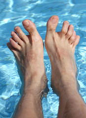 man's feet on the bathtub of a relaxing pool