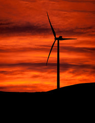 Sunset wind turbine on hill. Clean energy.