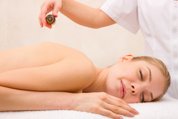 Obraz na płótnie Canvas Masseuse pouring massage oil woman's back