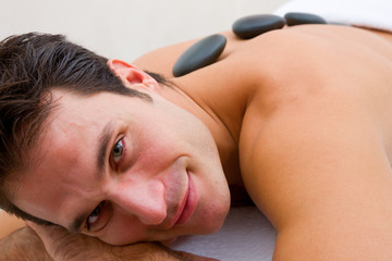 Smiling young man receiving hot stone treatment