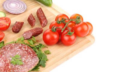 Sausage salami and vegetables on wooden platter.