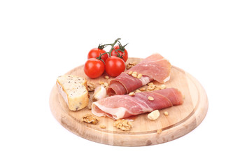 Prosciutto with tomatoes on wooden platter.