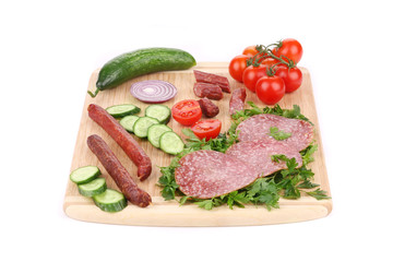 Fototapeta na wymiar Sausage salami and vegetables on wooden platter.