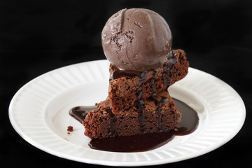 Slices of a brownie covered with chocolate ice cream