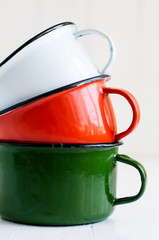 three bright colorful enameled mugs