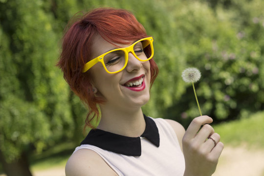Beautiful hipster teenage girl blowing a dandelion