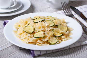 farfalle pasta with zucchini and cheese on a white plate