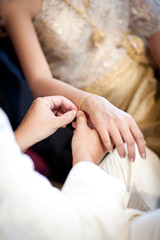 Obraz na płótnie Canvas groom wearing gold bracelet for his bride in wedding ceremony