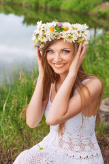 Cute young woman with circlet of camomile at the riverside © tananddda