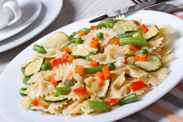 Italian pasta farfalle with slices of vegetables closeup