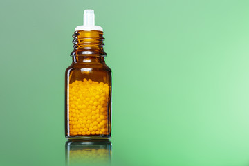 single bottle with homeopathy globules with green background