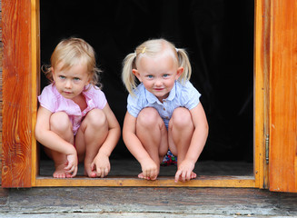 Funny kids in the doorway to an rural house.