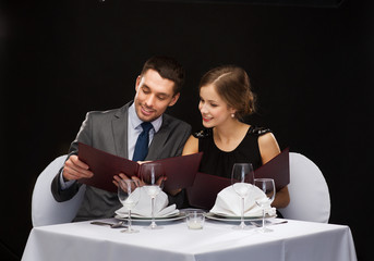 smiling couple with menus at restaurant