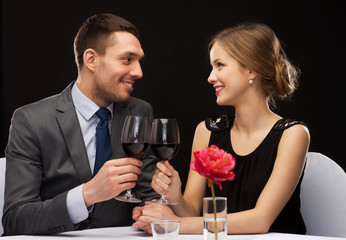young couple with glasses of wine at restaurant