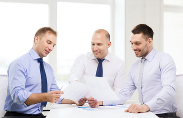 smiling businessmen with papers in office