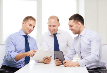three smiling businessmen with tablet pc in office