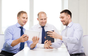 three smiling businessmen with tablet pc in office
