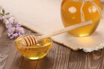 honey in a glass bowl on a wooden boards background