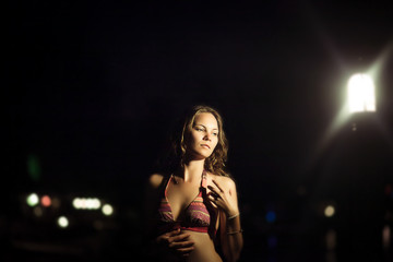 Obraz na płótnie Canvas Young beautiful woman in bikini against night on beach near