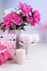 Composition of beautiful peonies in vase, tea in cup and