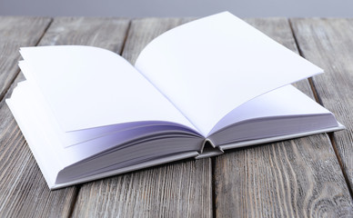 Open white book on wooden table, close-up