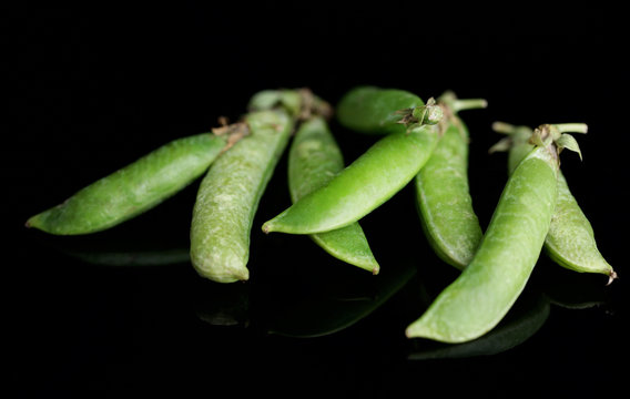 Fresh green peas isolated on black background
