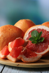 Ripe grapefruits on plate on color wooden background