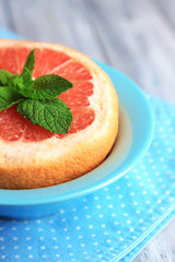 Ripe grapefruits in bowl on color wooden background