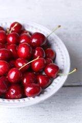 Sweet cherries in bowl on wooden background