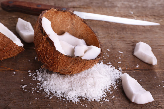 Broken coconut with knife on wooden background