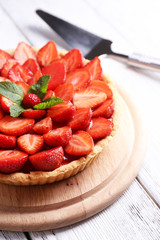 Strawberry tart on wooden tray, on color wooden background