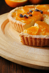Homemade orange tart with coffee grains on wooden background