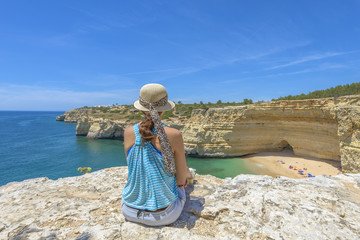 Young female tourist enjoying a beach view from a cliff
