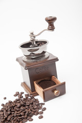 Isolated vintage coffee bean grinder and fresh ground coffee